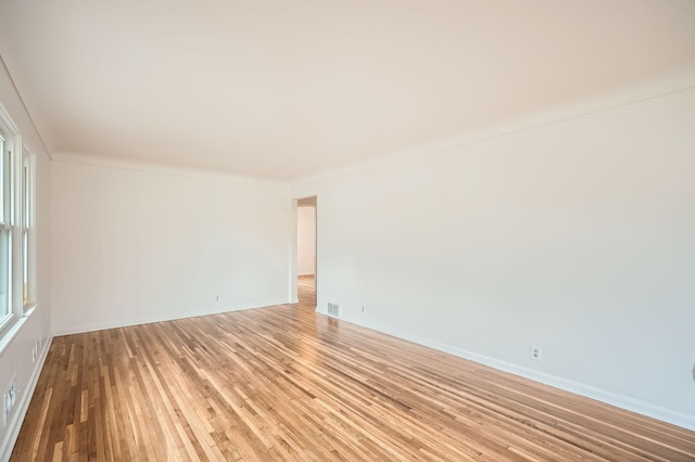 empty room with visible vents, light wood finished floors, and baseboards