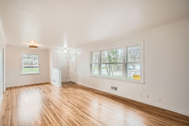 unfurnished living room featuring baseboards, visible vents, and light wood-style floors