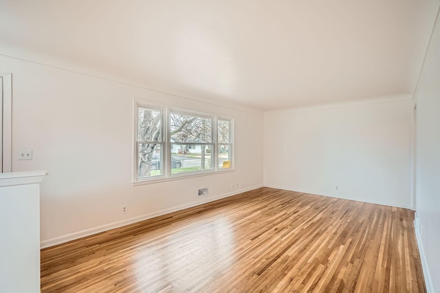unfurnished room featuring baseboards, visible vents, ornamental molding, and light wood-style flooring
