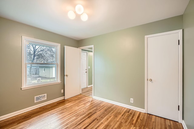 unfurnished bedroom featuring baseboards, visible vents, and light wood-style floors
