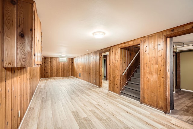 finished below grade area featuring wooden walls, stairs, and light wood-type flooring