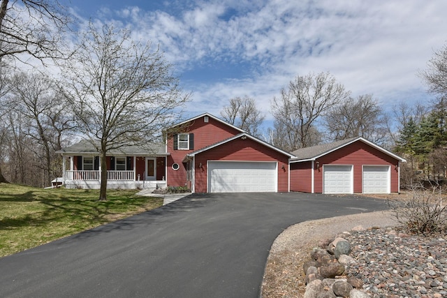 view of front of house with a garage, driveway, a porch, and a front lawn