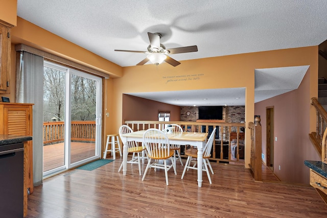 dining area with a ceiling fan, a textured ceiling, wood finished floors, and a fireplace