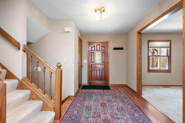 entryway featuring stairway, a textured ceiling, and wood finished floors