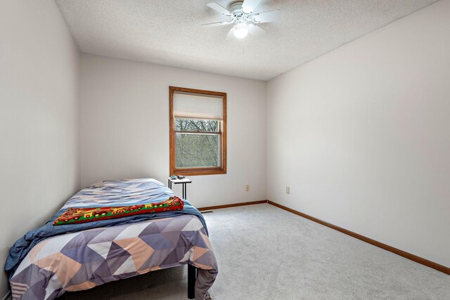 carpeted bedroom with a ceiling fan, a textured ceiling, and baseboards