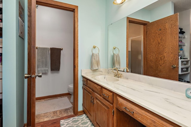 bathroom with toilet, a stall shower, wood finished floors, and vanity