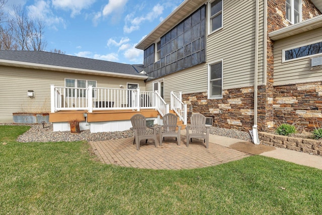 131 Norman Ave N, Foley, MN 56329 - back of house featuring a lawn, a patio area, a wooden deck, and stone siding