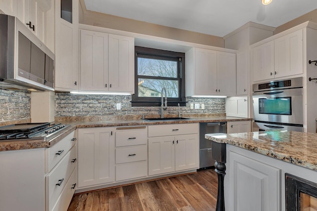 131 Norman Ave N, Foley, MN 56329 - kitchen featuring appliances with stainless steel finishes, a sink, light wood-style floors, white cabinetry, and decorative backsplash