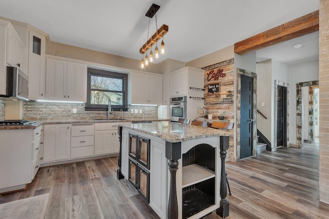 131 Norman Ave N, Foley, MN 56329 - kitchen featuring white cabinets, a sink, stainless steel appliances, decorative backsplash, and wood finished floors