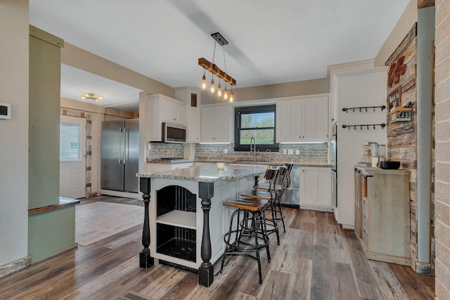 131 Norman Ave N, Foley, MN 56329 - kitchen with a sink, a center island, stainless steel appliances, white cabinetry, and decorative backsplash