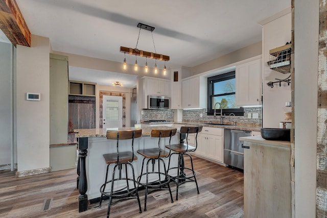 131 Norman Ave N, Foley, MN 56329 - kitchen featuring a sink, wood finished floors, tasteful backsplash, and stainless steel appliances