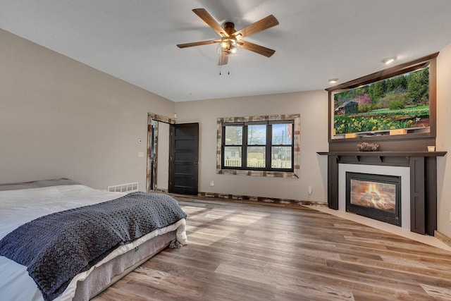 131 Norman Ave N, Foley, MN 56329 - bedroom featuring visible vents, a ceiling fan, a glass covered fireplace, and wood finished floors