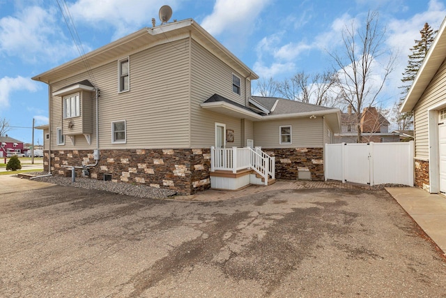131 Norman Ave N, Foley, MN 56329 - exterior space featuring roof with shingles, a gate, fence, aphalt driveway, and stone siding