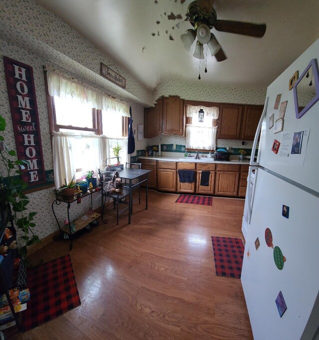 211 2nd St, Albert Lea, MN 56007 - kitchen featuring freestanding refrigerator, wallpapered walls, light wood finished floors, brown cabinets, and ceiling fan