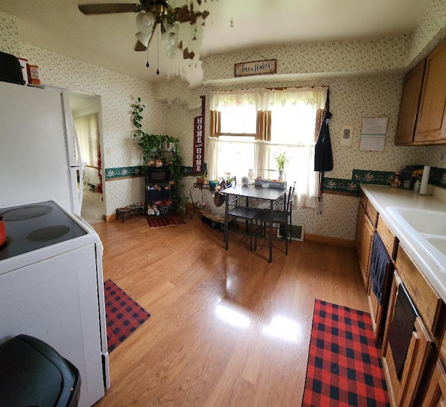 211 2nd St, Albert Lea, MN 56007 - kitchen with wallpapered walls, freestanding refrigerator, stove, light wood-style flooring, and ceiling fan