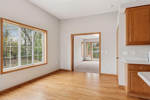 interior space with baseboards, brown cabinets, and light wood-style flooring