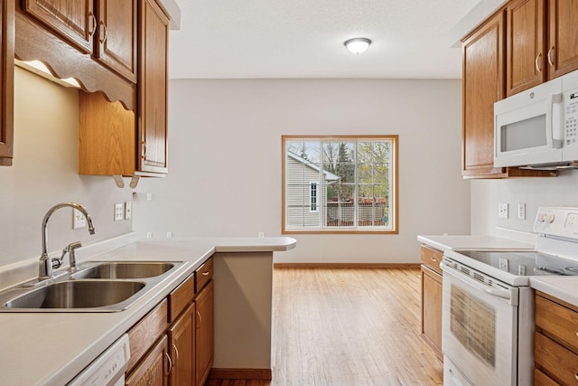 kitchen with white appliances, light wood-type flooring, light countertops, brown cabinets, and a sink