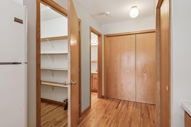 hall featuring light wood-style floors and a textured ceiling