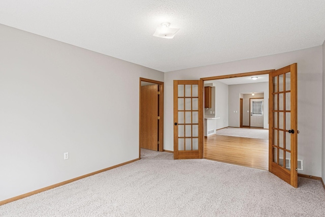 unfurnished room with baseboards, light colored carpet, french doors, and visible vents