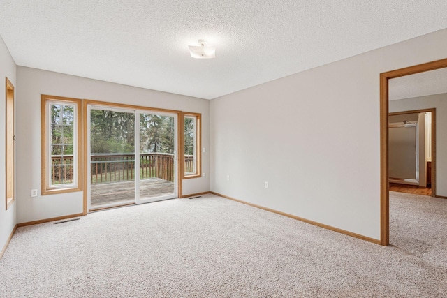 spare room with baseboards, carpet flooring, a textured ceiling, and visible vents