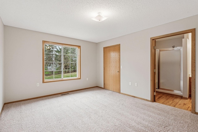 unfurnished bedroom with carpet flooring, a textured ceiling, baseboards, and visible vents
