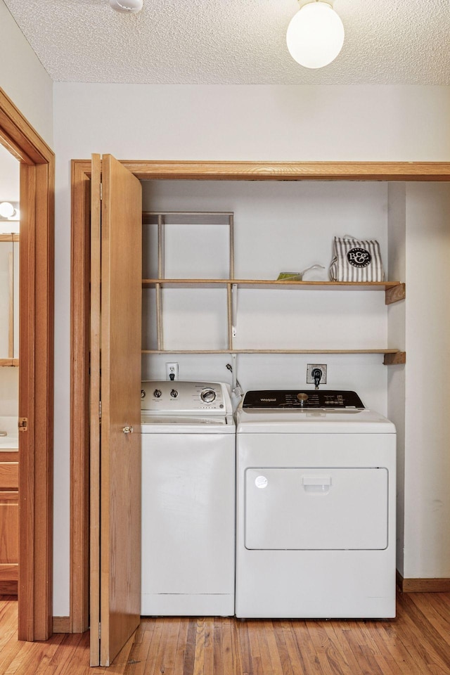 laundry room featuring laundry area, a textured ceiling, independent washer and dryer, and light wood-type flooring