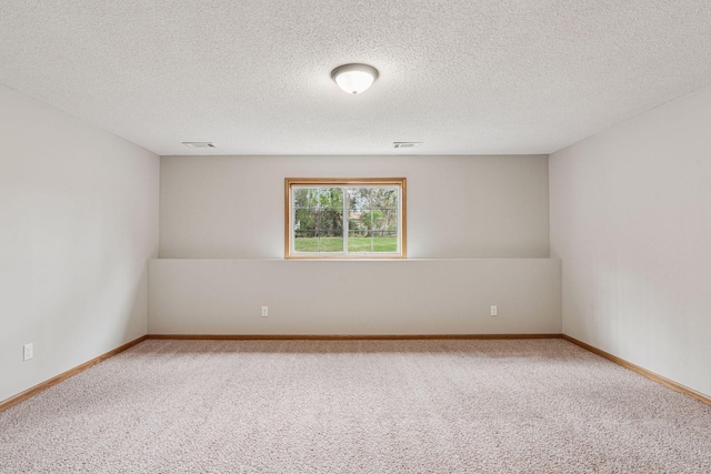 empty room featuring visible vents, carpet flooring, baseboards, and a textured ceiling