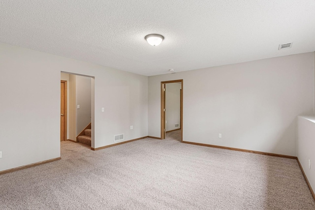 carpeted spare room with stairway, baseboards, and visible vents