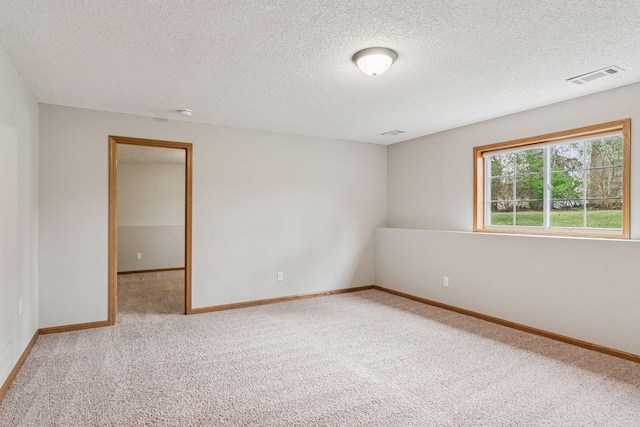 empty room featuring carpet flooring, a textured ceiling, visible vents, and baseboards