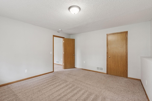 empty room featuring carpet flooring, a textured ceiling, and visible vents