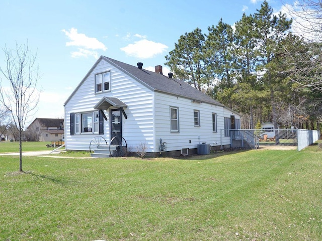 bungalow featuring roof with shingles, fence, central AC unit, and a front yard