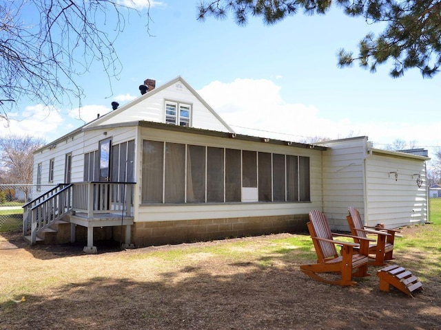 rear view of property with a chimney and a sunroom