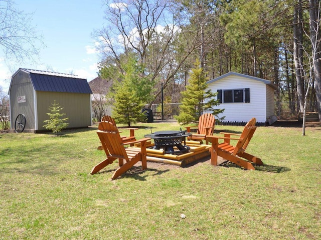 view of yard featuring an outbuilding, a fire pit, fence, and a storage shed