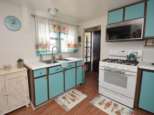 kitchen with gas range gas stove, wood finished floors, a sink, light countertops, and stainless steel microwave