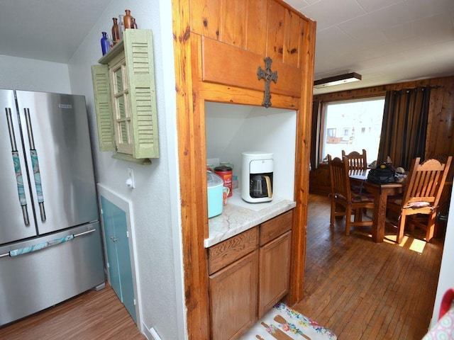 kitchen with brown cabinetry, freestanding refrigerator, wood finished floors, and light countertops