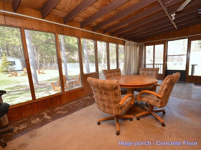 sunroom featuring wood walls and outdoor dining space