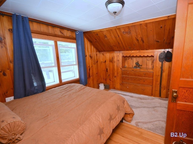 bedroom featuring wood walls and lofted ceiling