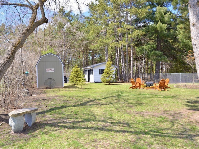 view of yard with a fire pit, fence, an outbuilding, and a shed