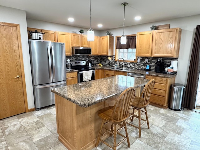 kitchen featuring a breakfast bar area, appliances with stainless steel finishes, tasteful backsplash, a center island, and a sink