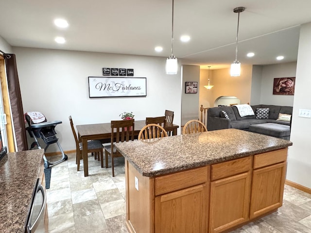 kitchen with dark stone countertops, recessed lighting, decorative light fixtures, baseboards, and a kitchen island