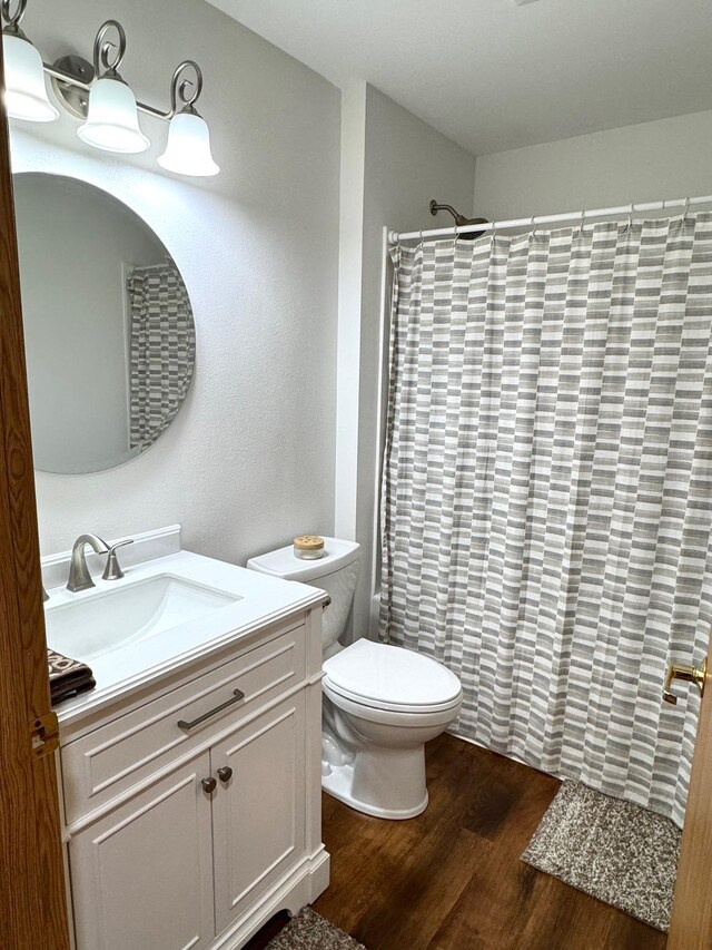 bathroom featuring vanity, curtained shower, toilet, and wood finished floors