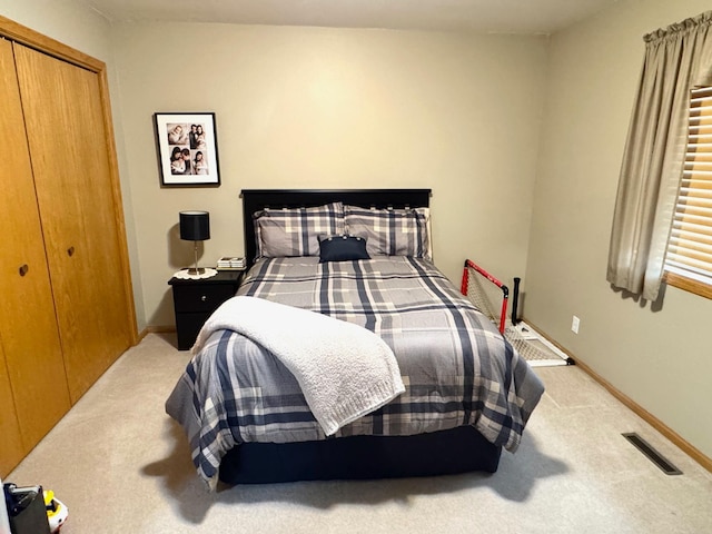 bedroom featuring visible vents, baseboards, a closet, and light carpet