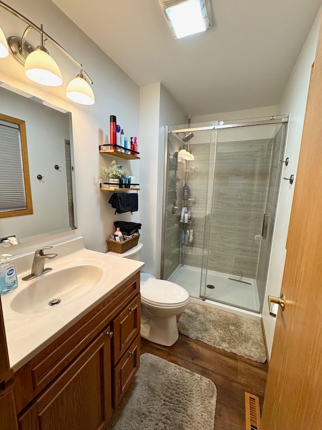 full bath featuring vanity, a shower stall, wood finished floors, and visible vents