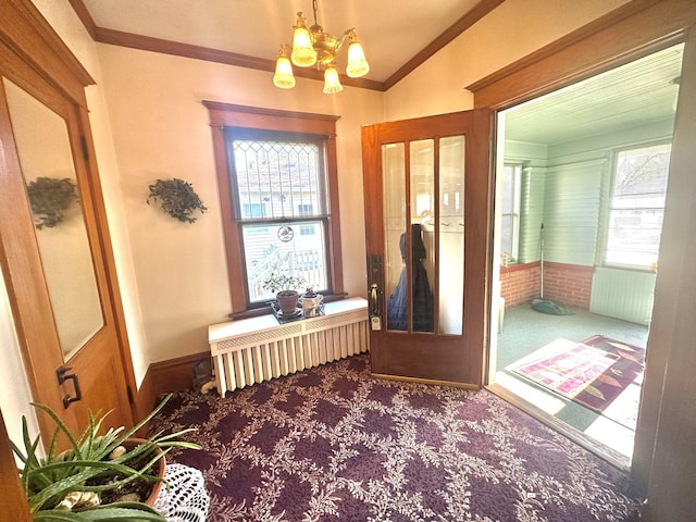 doorway to outside with carpet flooring, a chandelier, radiator heating unit, and crown molding