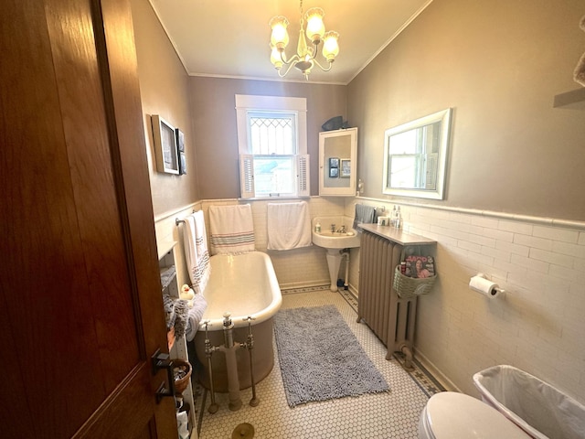full bathroom with a notable chandelier, ornamental molding, wainscoting, and a freestanding tub