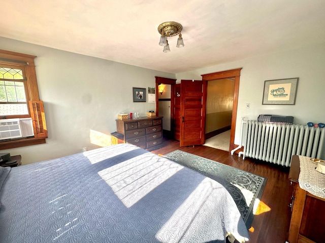 bedroom with radiator heating unit, wood finished floors, and cooling unit