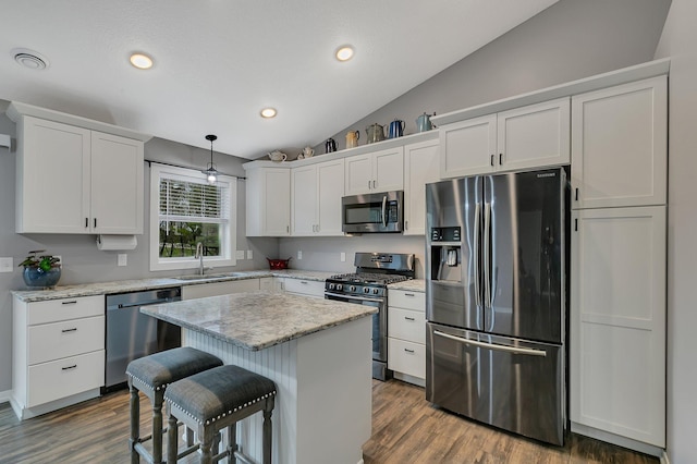kitchen with a breakfast bar area, white cabinetry, a sink, appliances with stainless steel finishes, and vaulted ceiling