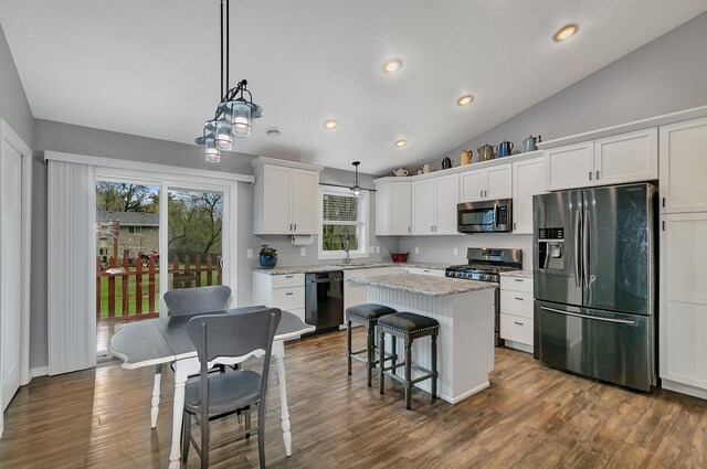 kitchen with appliances with stainless steel finishes, white cabinets, a kitchen island, and a wealth of natural light