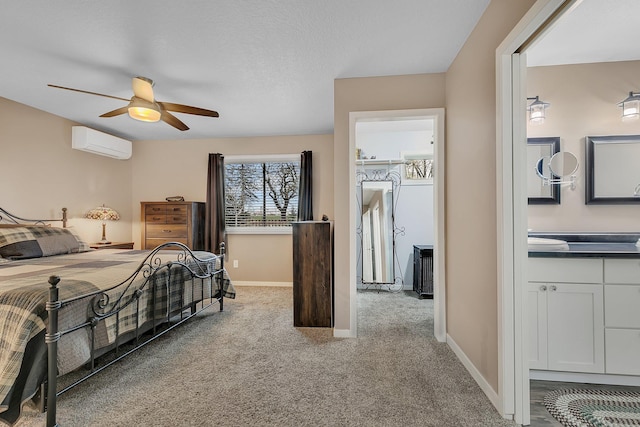 bedroom with carpet floors, a ceiling fan, baseboards, ensuite bathroom, and a wall mounted AC