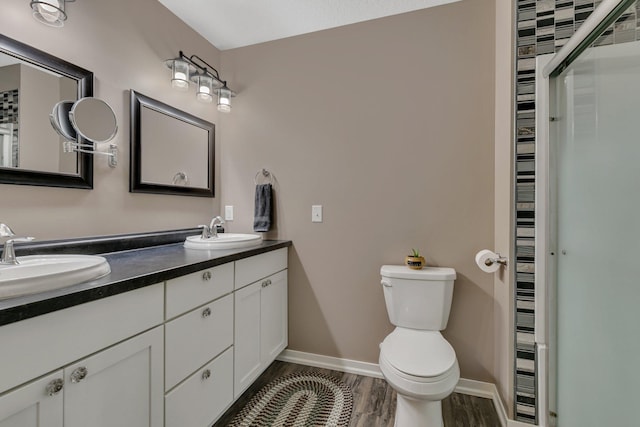 full bath with double vanity, toilet, a sink, and wood finished floors